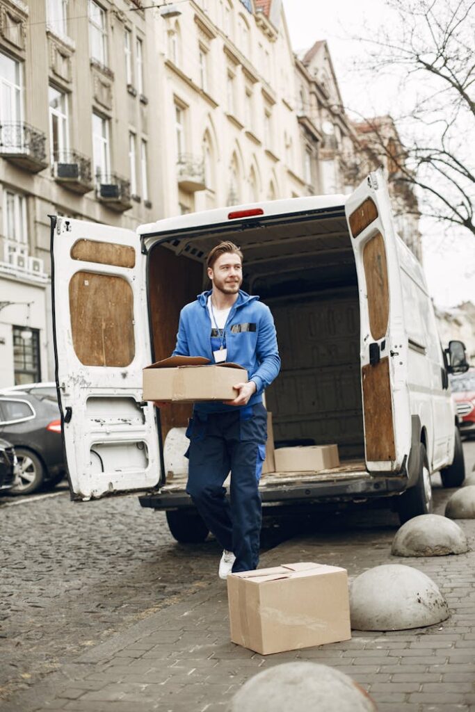 Courier unloading packages from a delivery van on a city street, wearing a blue uniform.