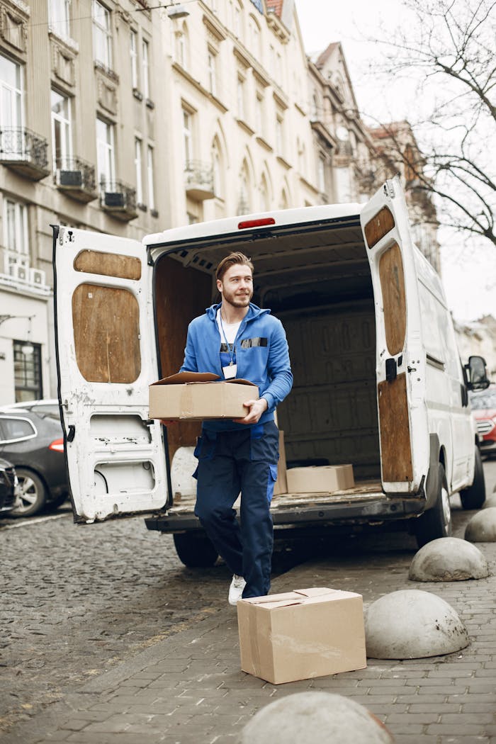 Courier unloading packages from a delivery van on a city street, wearing a blue uniform.